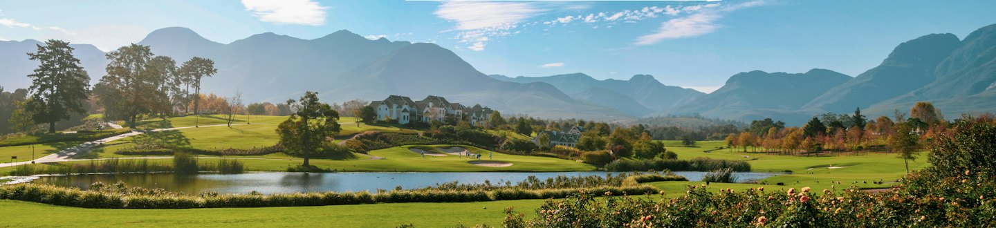 A golf course with a lake and distant mountains.