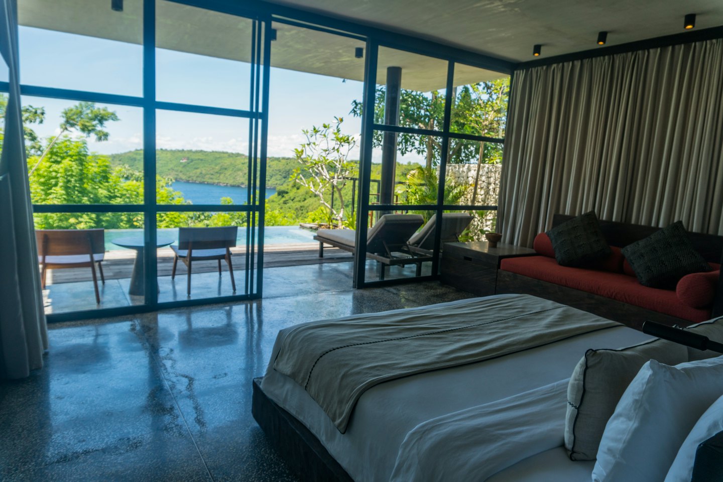 Luxury hotel room opens to patio infinity pool with bay view.