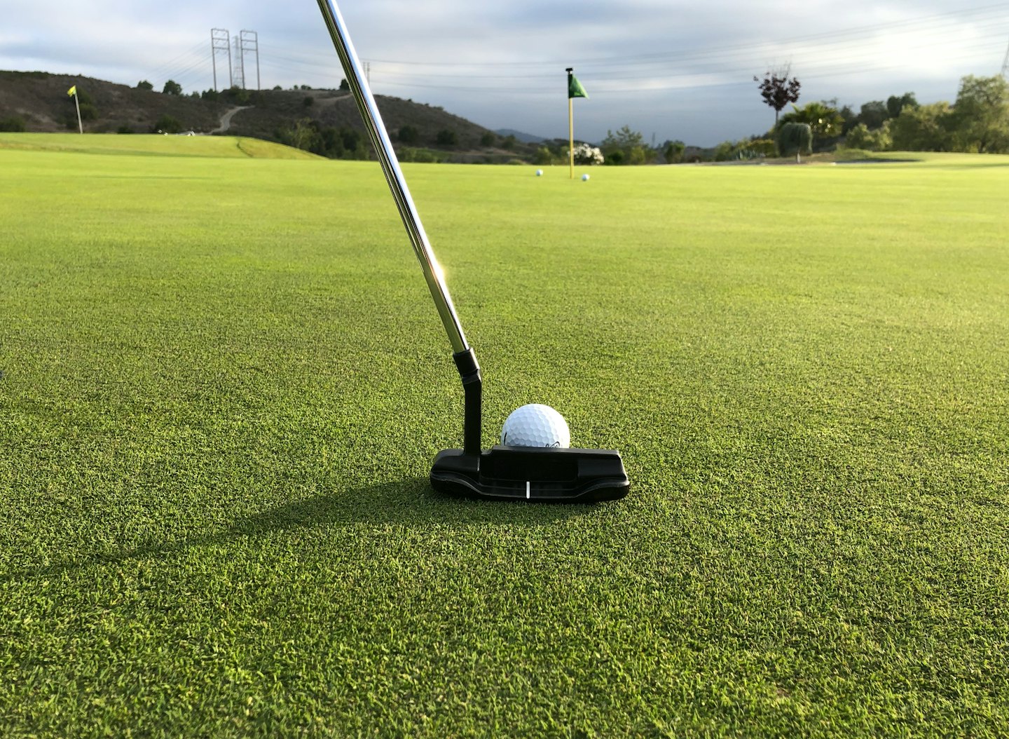 Golf putter ready to strike a white ball on a green.
